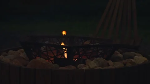 Golden Flames Dance Softly Inside a Decorative Metal Fire Pit at Nightfall Stock Footage 344860836