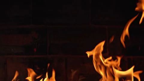 Golden Flames Flicker Against a Rustic Brick Wall at Night Stock Footage 346053569