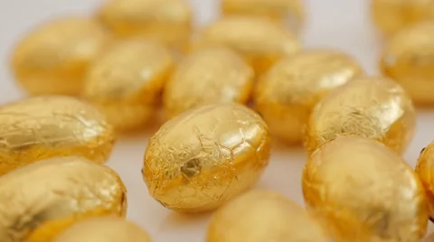 Golden foil wrapped  Easter chocolate eggs on white background panning 4K Stock Footage 55453088