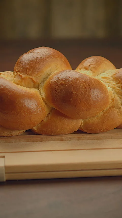 Golden Freshly Baked Braided Bread Beautifully Presented on a Wooden Board Stock Footage 287209448