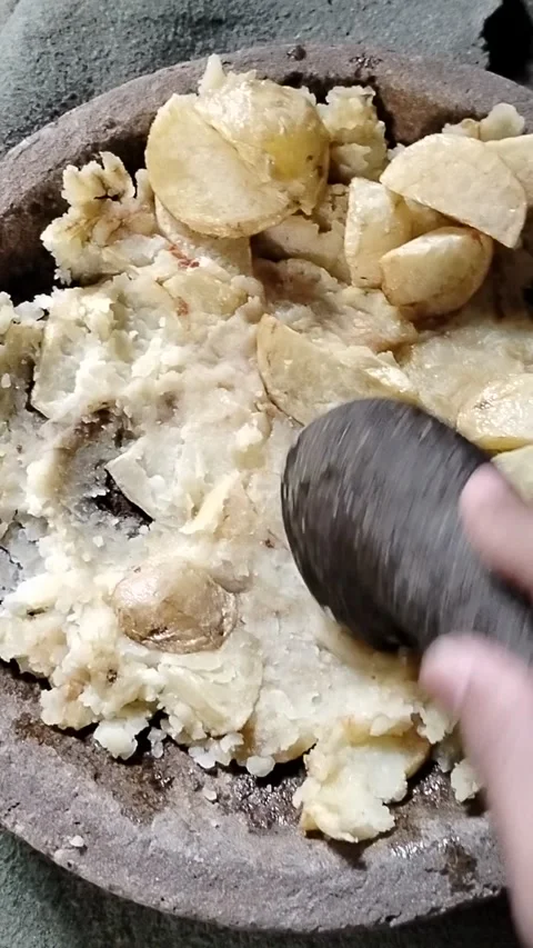 Golden fried potatoes placed in a stone mortar before being mashed by hand, show Stock Footage 336392396
