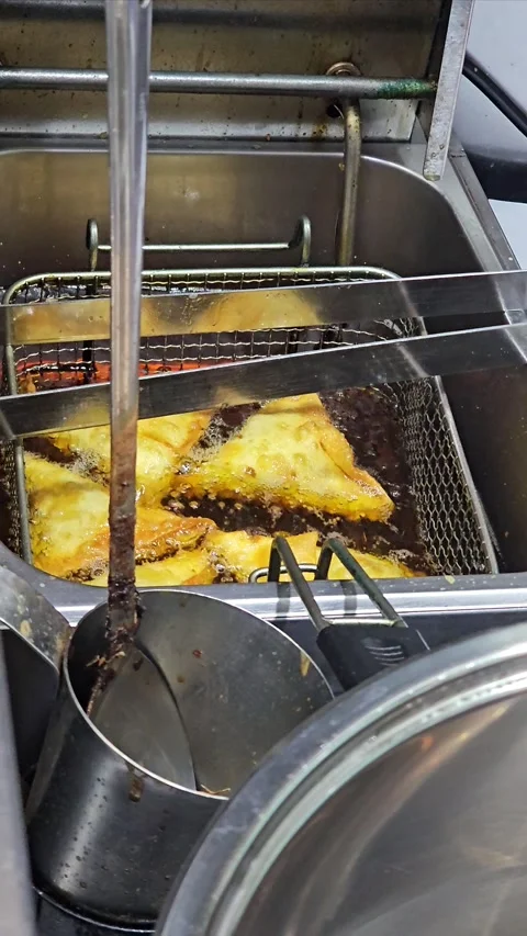 Golden-fried, triangular pastry samosa submerged in hot oil 스톡 동영상 311884947