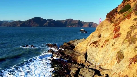Golden Gate Bridge Over Waves Crashing Into Beach Mountainside by Aerial Drone Видео 70328292