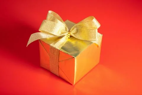 Golden gift box with bow over red background Stock Photos