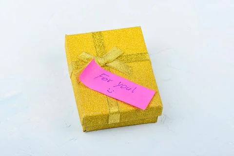 Golden gift box with a note on a light background. Stock-Fotos