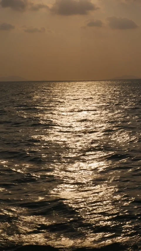Golden glare of the setting sun on the waves in the open sea. Reflections in the Stock Footage 312110314