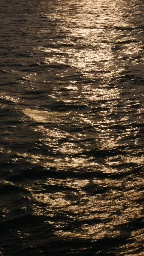 Golden glare of the setting sun on the waves in the open sea. Reflections in the Stock Footage 312337588