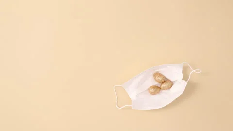 Golden glitter Easter eggs appear in face mask on nude background. Stop motion Stock Footage 150273538
