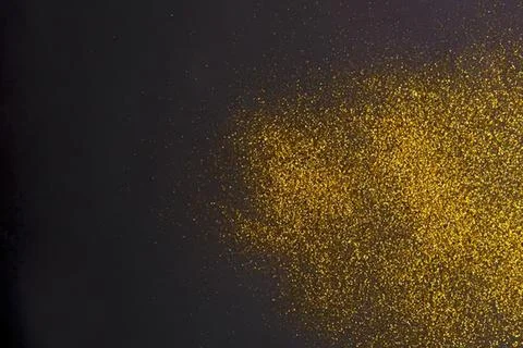 Golden glitter explosion on dark background Stock Photos