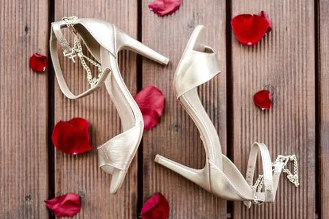 Golden high heel shoes with rose petals Stock Photos