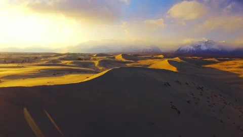 Golden hour light over desert sand dunes with mountains Stock Footage 337025472