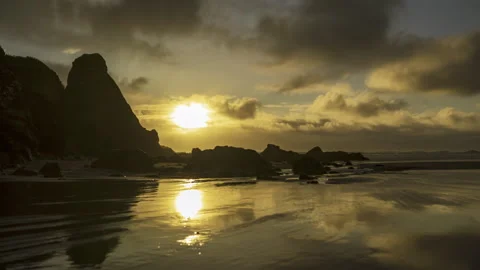 Golden hour sunset with clouds reflecting on a low tide wet beach - timelapse Stock Footage 220746372