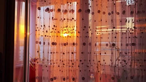 Golden hour sunset light streams through translucent decorative beaded curtain Stock Footage 340387217