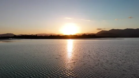 Golden Hour Sunset Over a Tranquil Lake and Distant Mountains Stock Footage 317095364