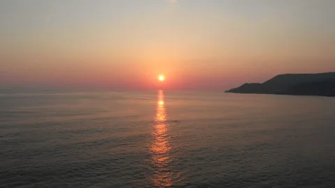 A golden idyllic sunset as the sun sets into the waters of the gentle ocean surf Video stock 130453013