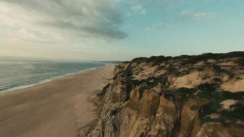 Golden light bathes sandy beach, cliffs rise steep Stock Footage 340227128