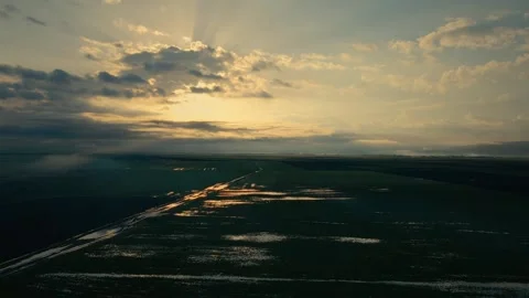Golden light breaks through stormy clouds above wetlands 스톡 동영상 332438893