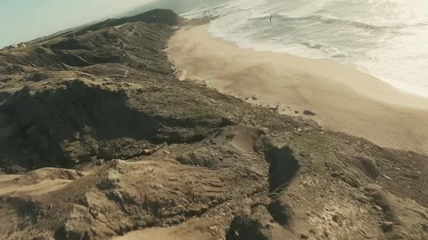 Golden light falls on rugged cliffs and sandy beach Stock Footage 341826394