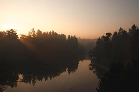 Golden light rays reflecting on misty lake at sunrise fall in Pruhonice park Stock Photos