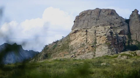Golden light touches rock wall on mountain through green leaves in central K Stock Footage