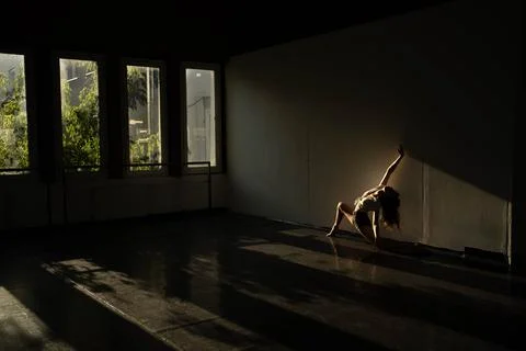 Golden lights shed on a dancer while practicing her moves alone Stock Photos
