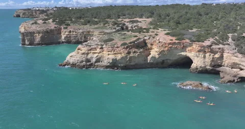 Golden limestone cliffs and sea cave with kayaks in Lagoa Algarve Stock Footage 346650915