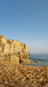 Golden limestone cliffs on a sandy Mediterranean beach with turquoise sea a.. Stockfoto's