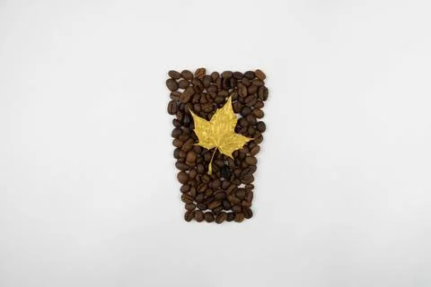 A golden maple leaf in coffee beans shaped like a glass Stock Photos