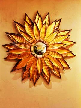 Golden metal mirror in the form of flower on yellow wall. Decor subject in the Stock Photos