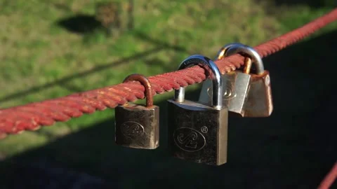 Golden padlocks locked to the bridge railing for luck in Lana river Stock Footage 256605900