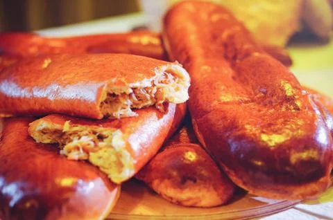 Golden pies with cabbage, pie split in half, home kitchen. Stock Photos