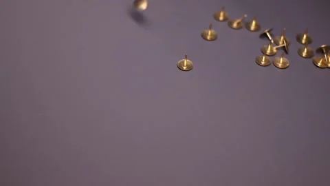 Golden pins falling on grayish background . stationery concept Stock Footage 147188797