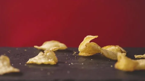 Golden potato chips falling on red background. food background. Salted potatoes  Stock Footage 149660606