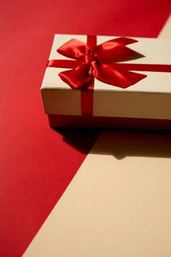 Golden present with red ribbon on the bright red background . Stock Photos
