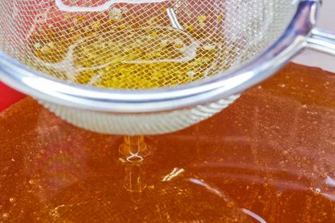 Golden Raw Honey Flowing Through Sieve Close-up Stock Photos