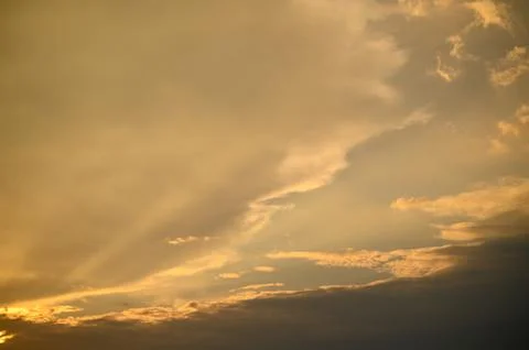 Golden rays illuminate the clouds during a serene sunset over the horizon Stock Photos