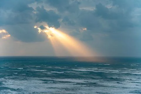 Golden rays of the sun breaking through the storm clouds Stock Photos