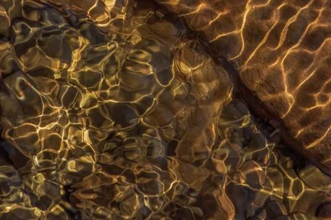 The golden reflection of the sunlight on the waves of the river Pomeca stream 스톡 사진