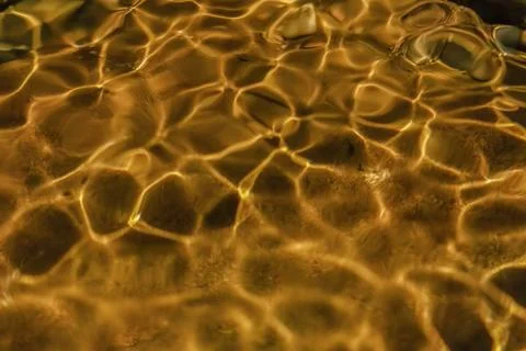 The golden reflection of the sunlight on the waves of the river Pomeca stream Foto stock