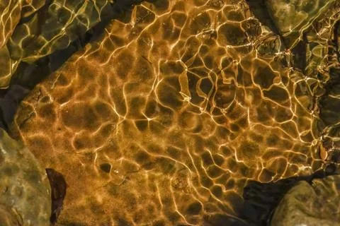 The golden reflection of the sunlight on the waves of the river Pomeca stream Stock Photos