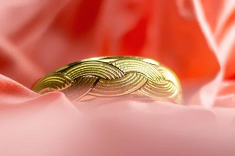 Golden ring, close up patterned golden wedding ring on pink cloth background Stock Photos