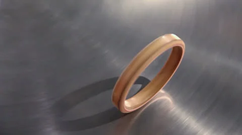 Golden ring roll by metal disk surface which spins, closeup Stock Footage 22734001