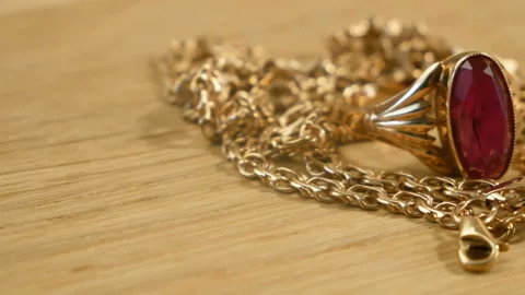 Golden ring with ruby stone and chain in wooden background,, rotating, vintag Stock Footage 160808349