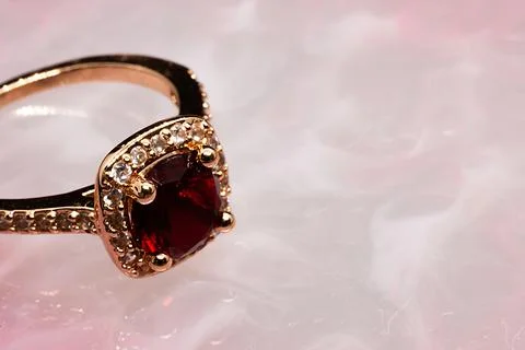 Golden ring with ruby stone on pink marble background 스톡 사진