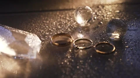 Golden rings lie on black table with water drops Stock Footage 172192579