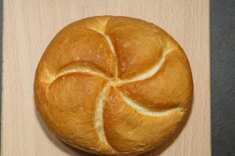 Golden round bread roll with a five-part swirl pattern on a light fabric ba.. Stock Photos