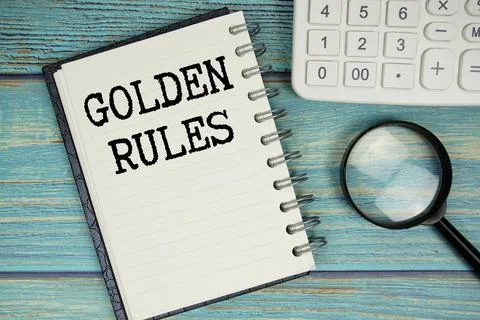 Golden Rules text on notepad with magnifying glass and calculator on wooden.. 스톡 사진