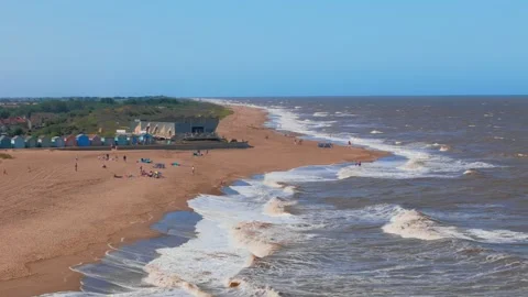 Golden sand meets rolling waves under bright blue skies. Small waves crash with Stock Footage 342025485