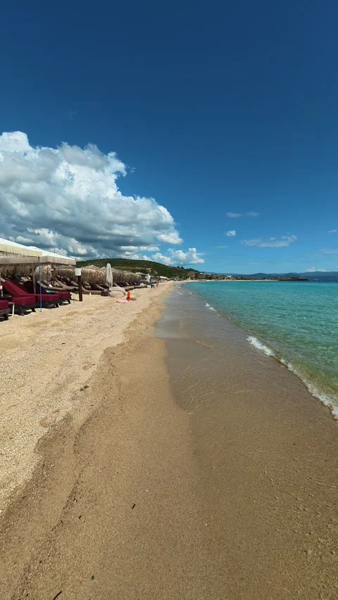 Golden sand meets turquoise waves under bright blue sky. Trani Ammouda, Vertical Stock Footage 340651553