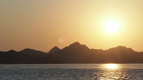 Golden sky, mountain silhouettes over the ocean, sunset Stock Footage